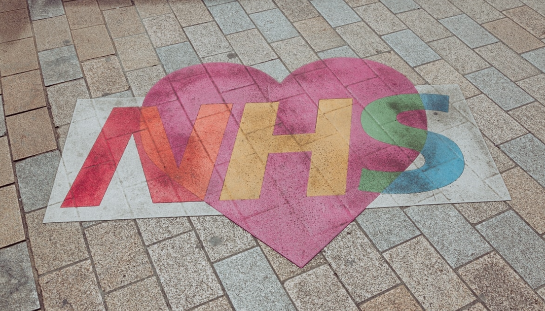 NHS logo with rainbow design and pink heart painted onto the pavement